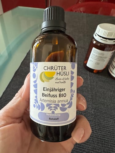 Kunden-Foto von einer Hand, die eine braune Glasflasche mit dem Produkt Beifuss einjährig Bio hält.