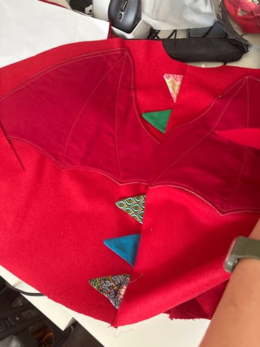 Reviewer's Plain Wool Blend Fabric sewn into a bright red dragon cape with fabric wing and triangle detail.