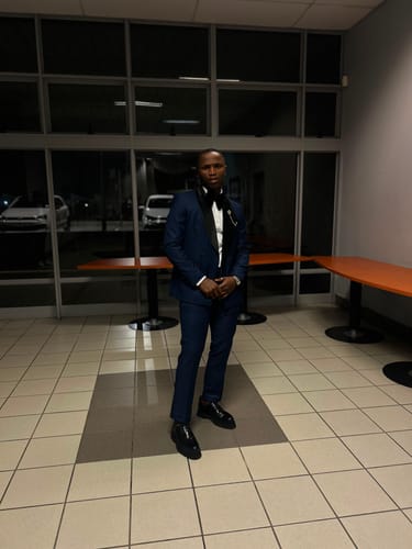 Customer wearing sleek black Lufiano lace-up shoes paired with a formal blue suit while standing in a hallway.