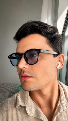 Customer's Óculos de Sol Jurerê in black frame, worn by a person with a neutral expression.
