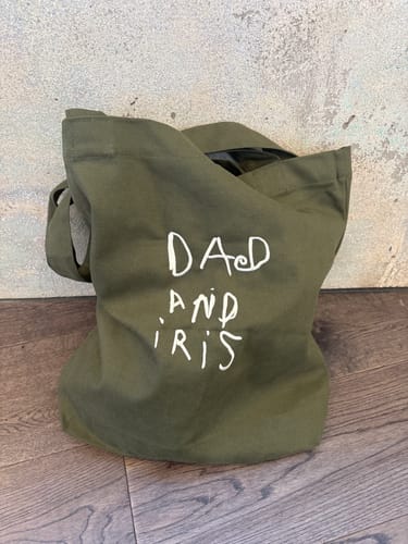 Customer's olive green canvas tote embroidered with white hand-drawn text reading Dad and Iris.