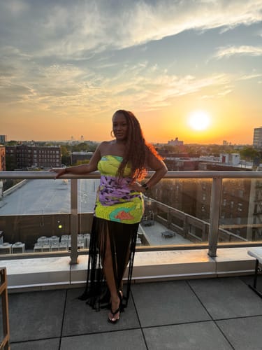 Reviewer's Naked Print Fringe Tube Dress featuring abstract botanical print and black fringe on a rooftop at sunset