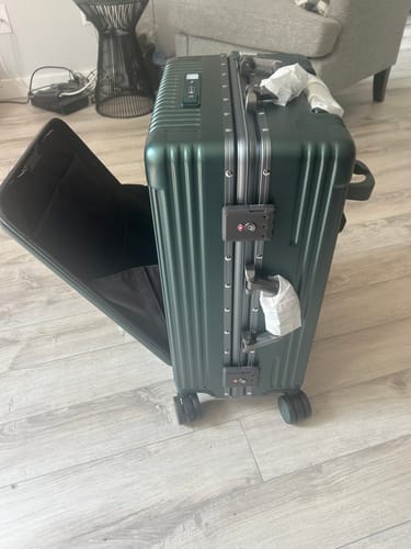 Customer's green carry-on luggage with the front compartment unzipped and slightly open.