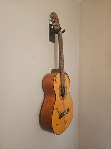 Customer's sort vegghengt gitarholder montert på vegg med en gitar hengende i den.