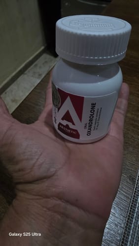 Customer's hand holding a white bottle of Aesthetic OxanX 10 supplement with red branding.