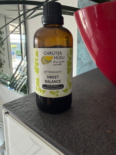 Kundenfoto der braunen Glasflasche SWEET BALANCE von Chrütterhüsli, stehend auf einer dunklen Ablage.