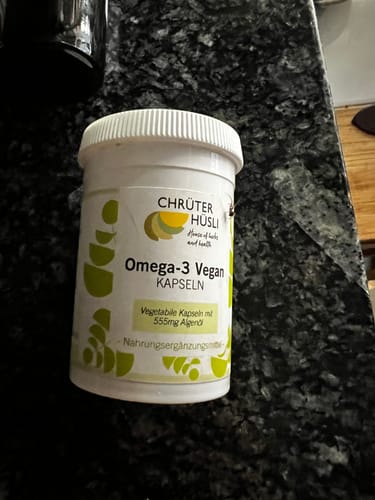 Customer's weiße Dose der Omega-3 Vegan Kapseln auf einem dunklen Steintisch.