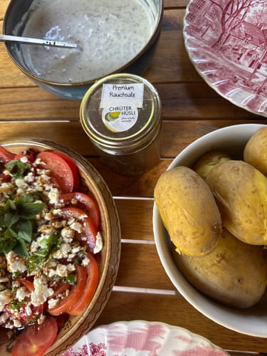 Kundenfoto von dänischem Premium Rauchsalz im Glas, neben einer Schüssel mit Kartoffeln und einem Tomatensalat.