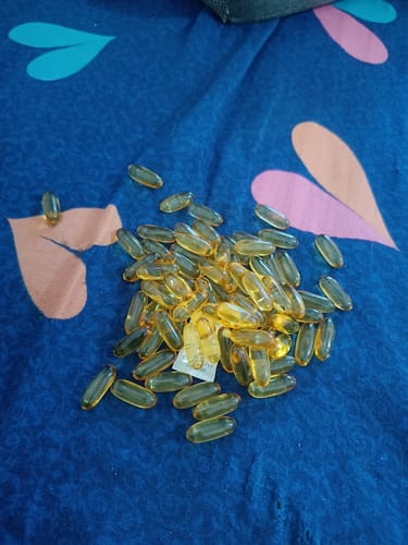 Customer's YouWeFit Omega-3 Fish Oil capsules spread across a blue patterned fabric surface.