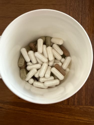 Customer's Magnesium Tria Kapseln capsules, with white and brown varieties, shown inside a white cup.