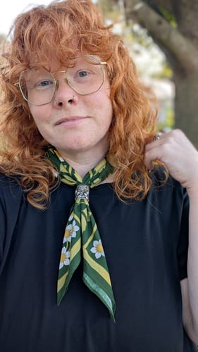 Customer's green floral Leaflet Bandana worn tied around their neck with a silver clip.