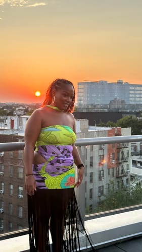 Reviewer's Naked Print Fringe Tube Dress, showing ruched waist and strapless bodysuit fit on a balcony at sunset