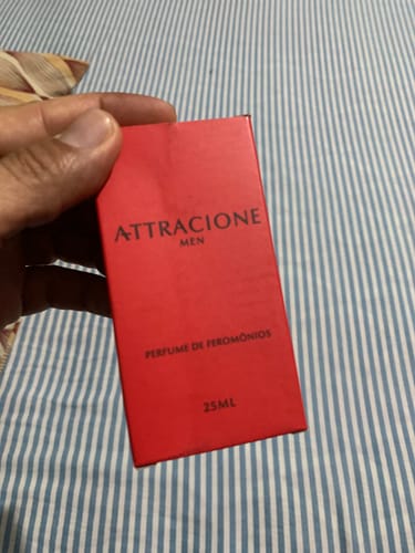 Customer's hand holding a red rectangular Attracione Men perfume box with 25ml text visible.