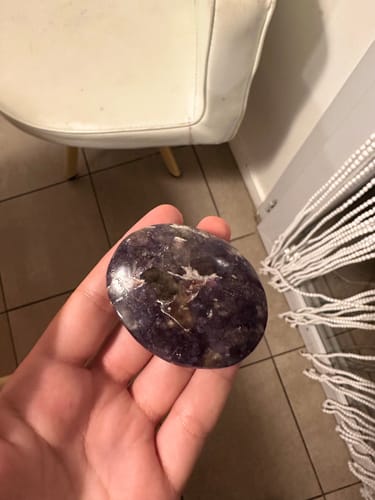 Customer's Lépidolite Galet, a smooth, deep purple stone held in a person's hand.