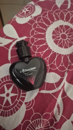 Customer's heart-shaped black Perfume Attracione Sensual bottle resting on a red and white floral patterned fabric.