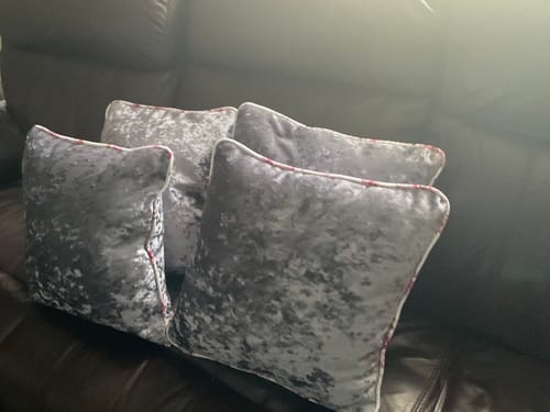 Customer's four grey marble crushed velvet cushions arranged on a dark leather sofa.