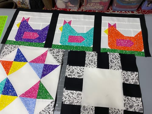 Customer's progress on Funky Chickens quilt kit showing sewn, colorful chicken blocks and pieced fabric sections.