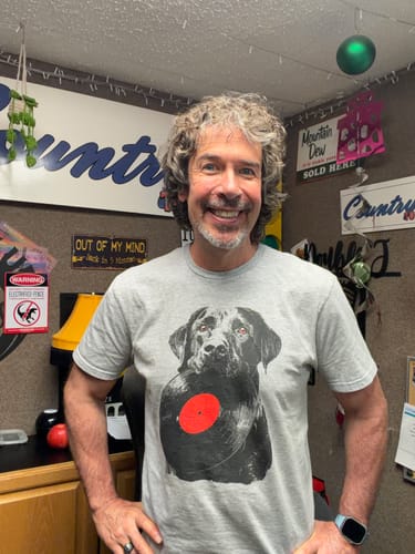 Customer's Labrador Vinyl T-Shirt, a grey cotton tee with a labrador and vinyl record graphic, worn in an office.