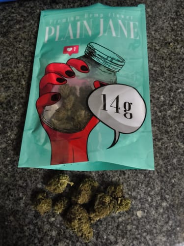 Customer's Oreoz flower buds sitting in front of a 14g Plain Jane packaging bag on a textured surface