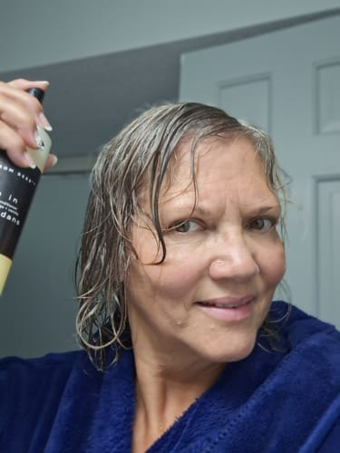 Customer's Leave-In Conditioner being applied to hair, showing shiny, smoothed gray hair.