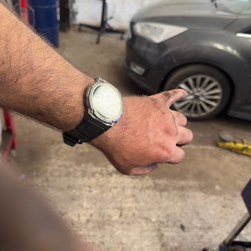 Reviewer's arm wearing a black Gard Pro Ultra 3 watch in a workshop, close-up.