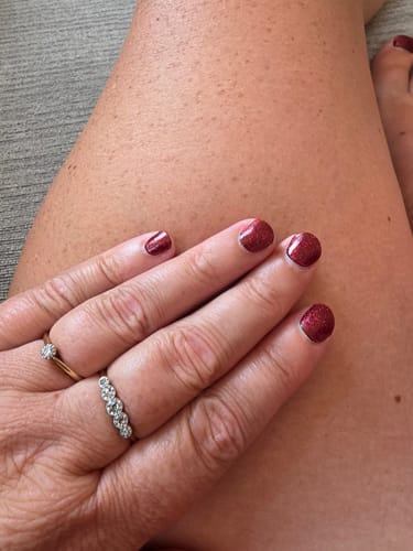 Customer's hand with shiny red gel nails from the Holy Gels Starter Kit.