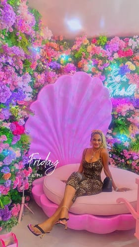 Customer's Naked Print Capri Jumpsuit worn on a shell-shaped chair in a floral setting.