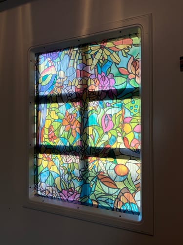 Customer's Tulia vindusfolie installert på et dørvindu med fargerikt blomstermotiv og dagslys.