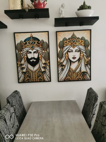 Customer's two Il Moro Regale and La Mora Regale portraits in black frames displayed on a wall above a table.