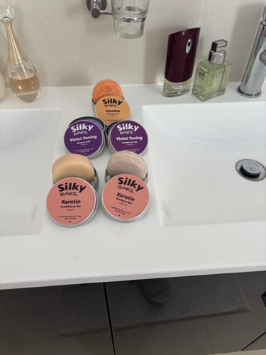 Reviewer's Keratin Strength & Repair Conditioner Bar and other Silky Bars products arranged on a bathroom sink.