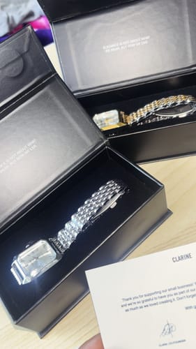 Customer's Clarine watches in open black display boxes with a note, showcasing the elegant metallic bracelets.