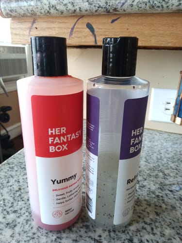 Customer's two Her Fantasy Two Pack Wash bottles, one pink and one clear, sitting on a kitchen counter.