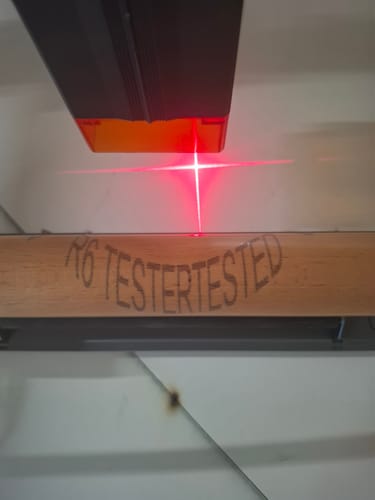 Customer's AtomStack R8 Pro engraving R6 TESTERTESTED into a wooden cylinder with a red laser crosshair guide.