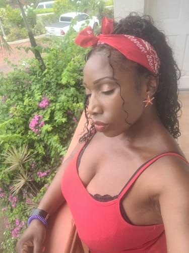 Customer's Water Wave hair extensions styled in a boho look with a red bandana, outdoors.