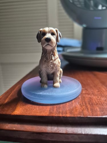 Customer's Personalized Pet 3D Figurine, a tan dog sitting on a circular iridescent base on a wooden desk.