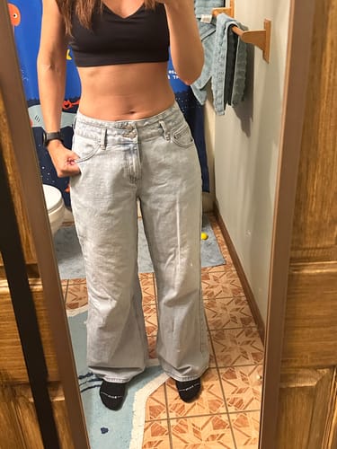 Customer's light-wash jeans worn in a mirror reflection, showing a relaxed fit and waist detail.