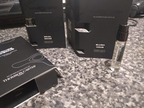 Customer's Blush Hour perfume sample vial and black product boxes on a grey speckled counter.