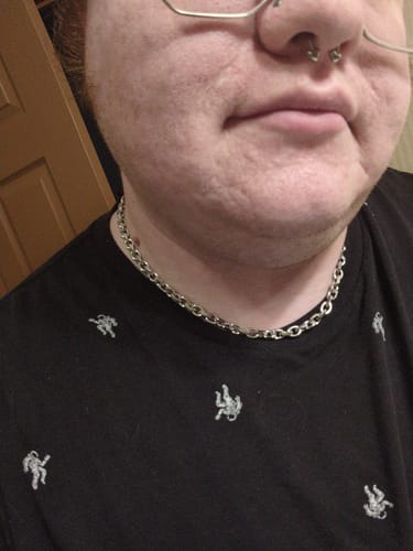 Customer's silver Aries Chain worn as a necklace, showing the interlocking links against a black patterned shirt.