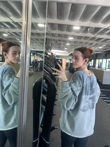 Customer's Golden Era Pump Cover Crewneck in grey, worn by a reviewer in a gym mirror selfie.