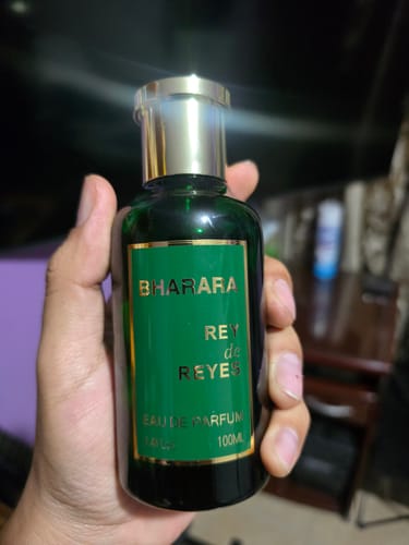 Reviewer's hand holding the Bharara Rey de Reyes perfume bottle, a sleek green glass bottle with gold accents.
