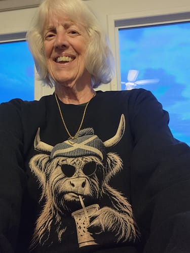 Customer's black Highland Cow Beanie Sweatshirt showing the graphic of a cow wearing sunglasses and a beanie.