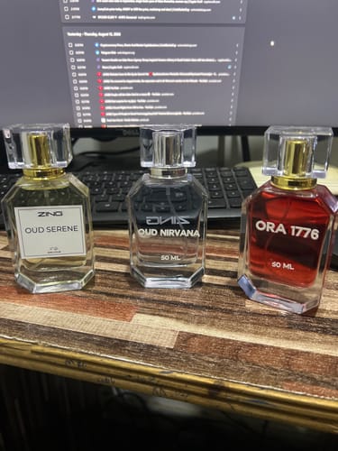 Customer's three OUD Supreme Bundle fragrance bottles, one gold-tinted, one clear, and one red, on a desk.