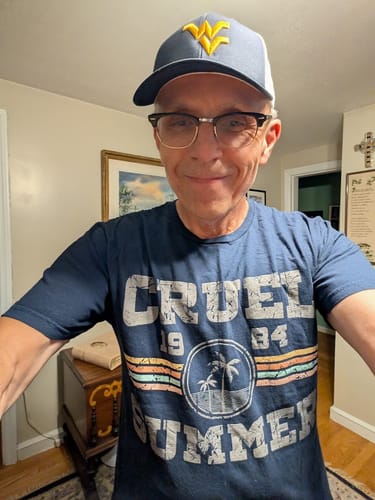Customer wearing a navy blue Cruel Summer 1984 T-shirt with a vintage-style palm tree graphic.