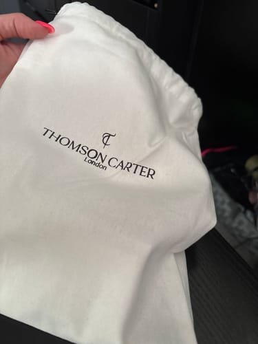 Customer's cream-colored drawstring pouch featuring the Thomson Carter logo.