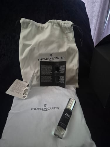 Reviewer's Rouge Avenue Eau de Parfum bottle, instructions, and two white branded cloth pouches.