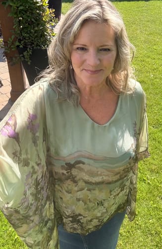 Customer's Meo Silk Wildflower Blouse in olive with a floral print worn outdoors.