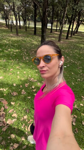 Cliente usando óculos de sol Maresias com armação alaranjada e lentes escuras em um parque gramado.