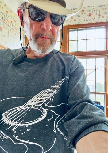 Reviewer wearing a charcoal long-sleeve Guitar Sketch shirt with a white graphic print.