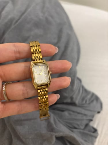 Customer's Isabell Petite Gold watch with a metallic gold band held in a hand.