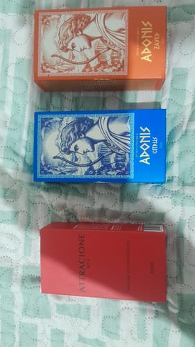 Customer's Kit Adonis and Attracione Men perfume boxes, showcasing one orange, one blue, and one red rectangular package.